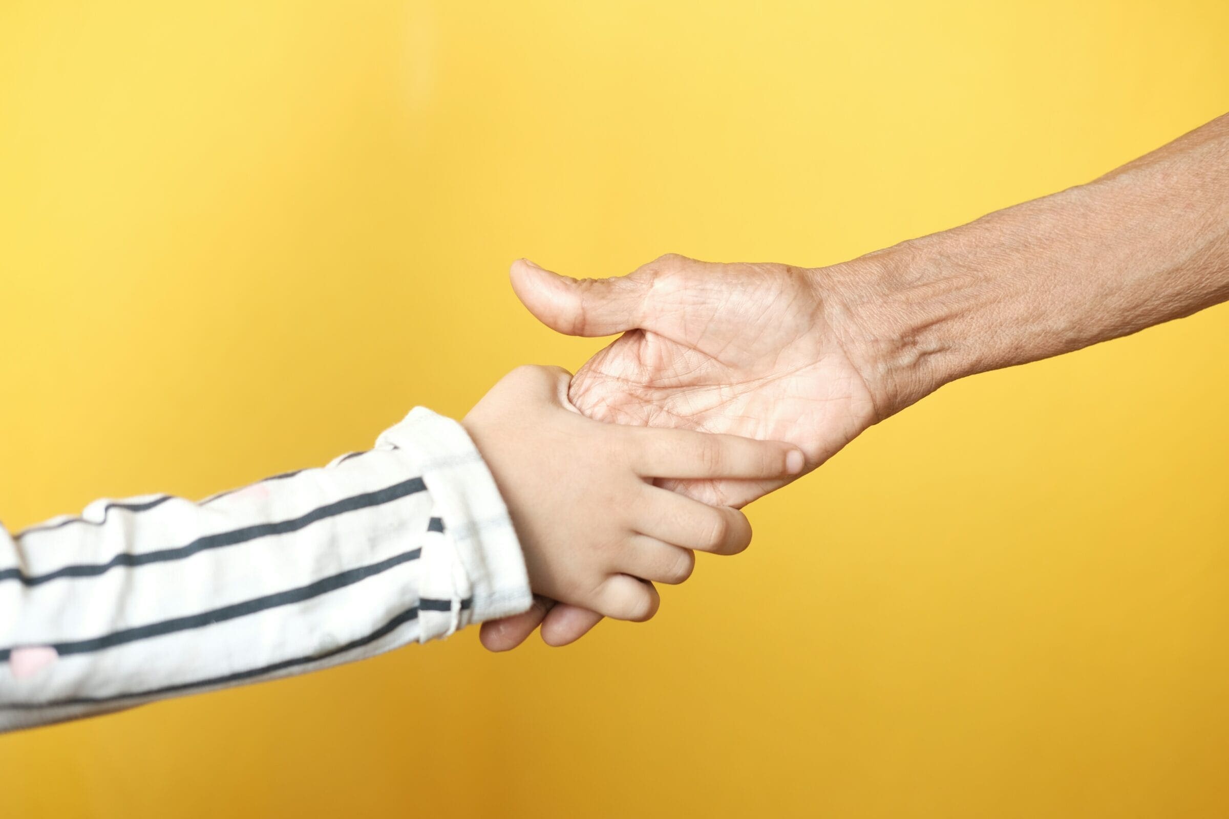 An image of an elderly and a young person holding hands.